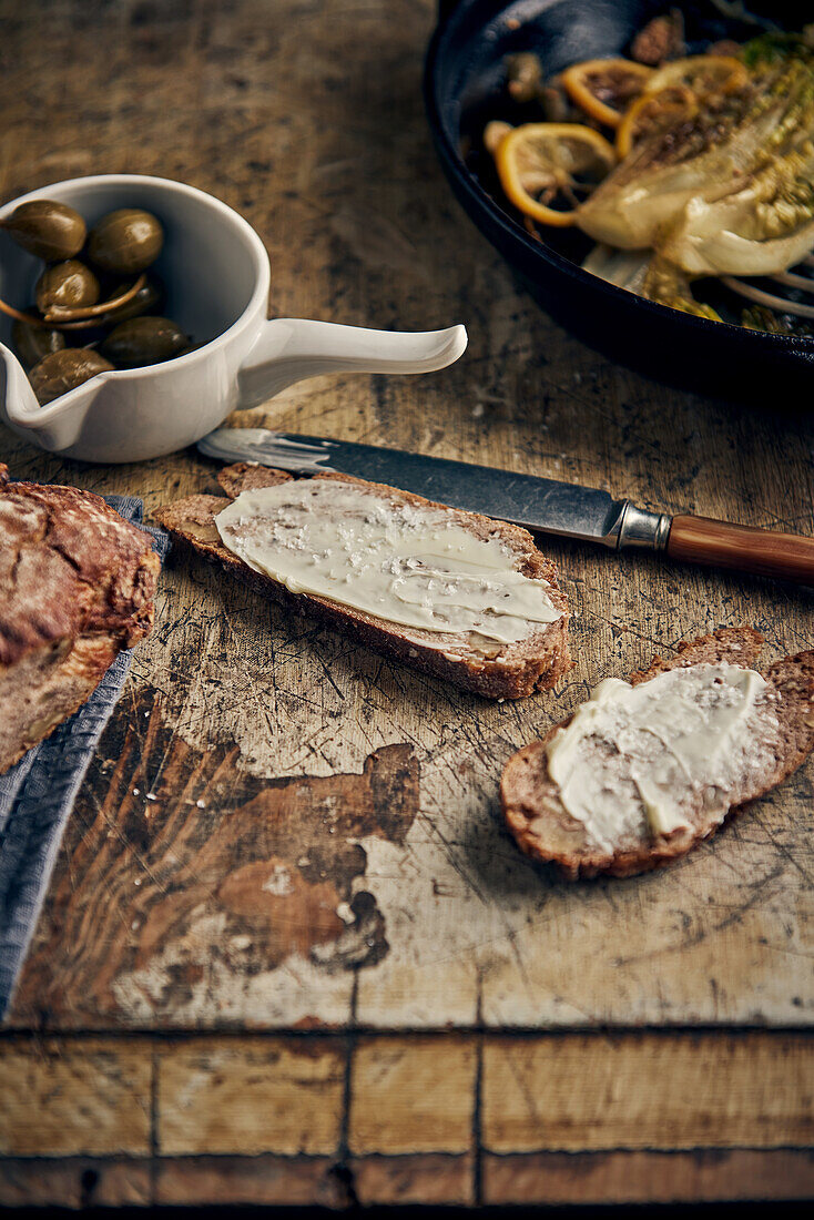 Butterbrot mit Kapernäpfeln, im Hintergrund gegrillter Romanesco