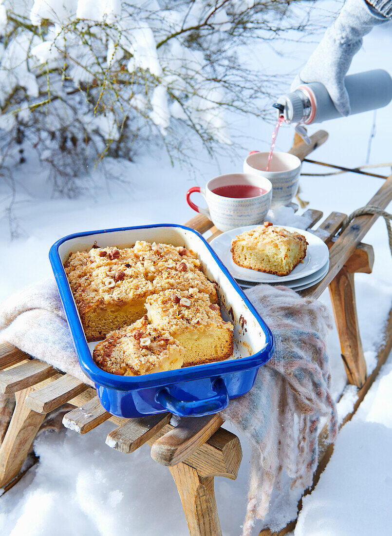 Birnenkuchen mit Nussbröseln auf Schlitten im Schnee