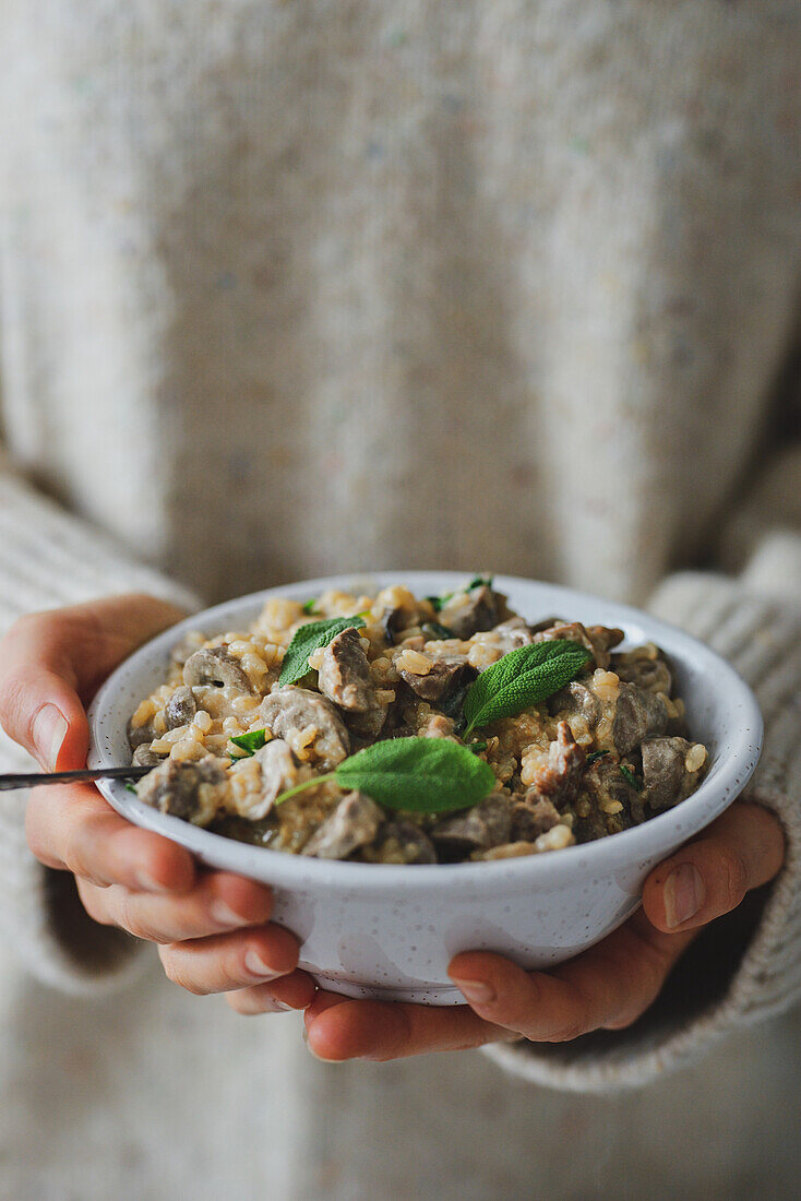 A bowl in hands with a healthy dinner of porridge and a duck