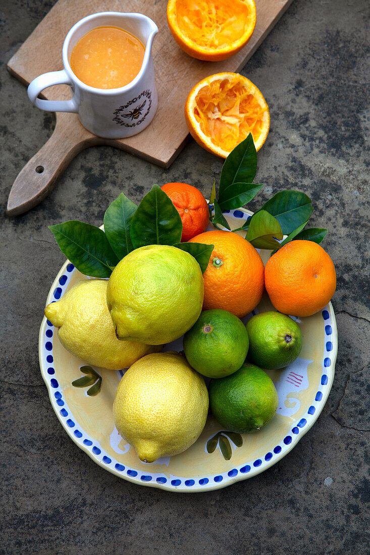 Zitrusfrüchte mit Blättern und frisch gepresstem Orangensaft