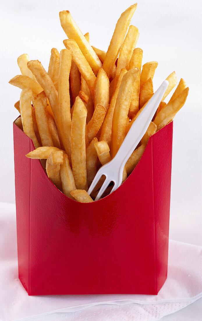 Pommes frites in roter Box mit Plastikgabel