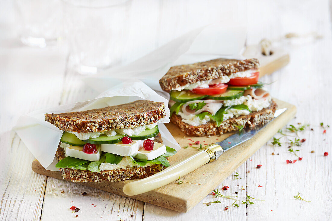 A cucumber-and-cheese sandwich and a ham sandwich with cream cheese and tomatoes