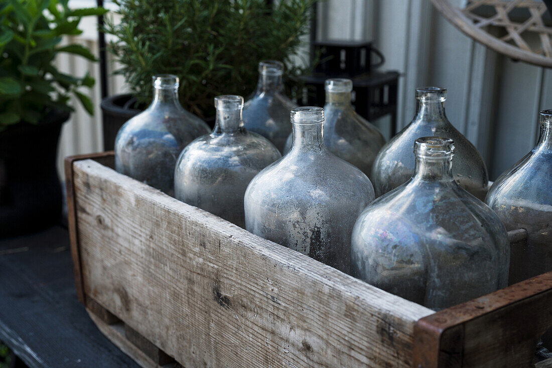 Vintage demijohn bottles in wooden trough on garden table