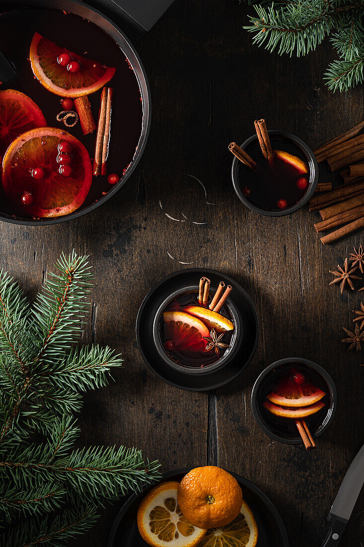 Glühwein in Tassen mit Orangenscheiben und Gewürzen auf Holztisch