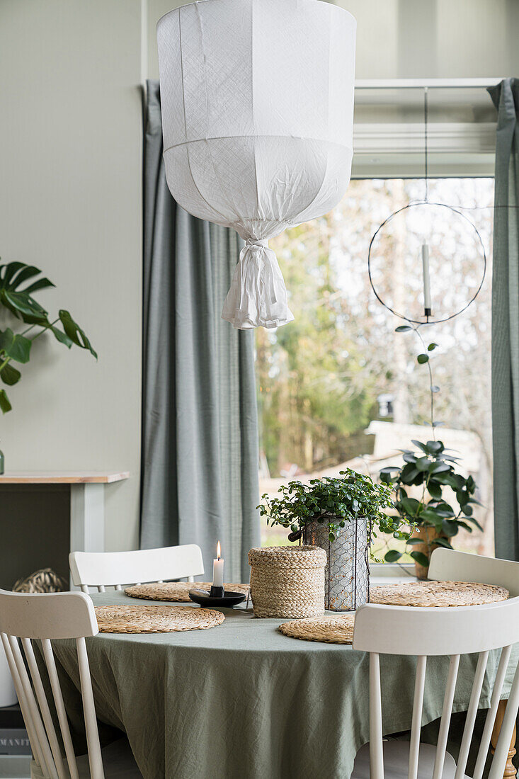 Runder Tisch mit Tischdecke und Holzstühle vor dem Fenster