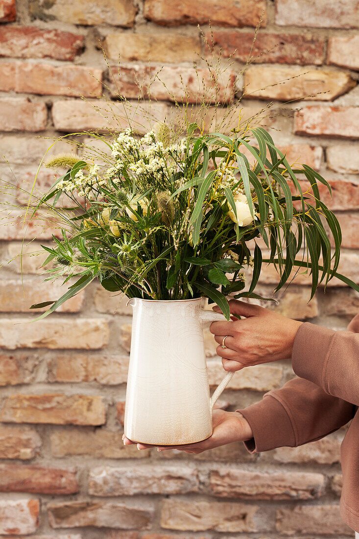 Blumenstrauß aus Gräsern, Rosen, Eukalyptus, Diestel und Strandflieder in Krugvase