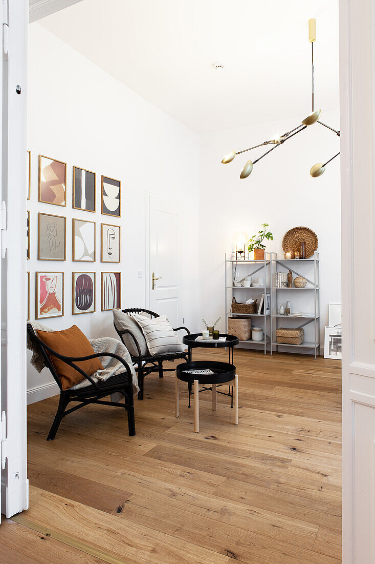 View into living room with black chairs, side table and gallery of pictures on wall