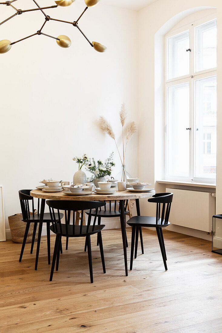 Set round table with black chairs next to window in period apartment