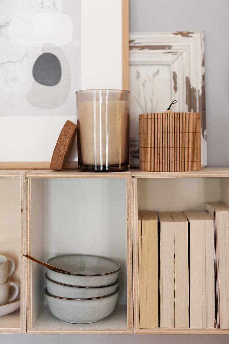 Dishes, books and candle on wall-mounted shelves