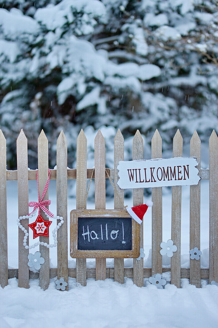Welcome signs on the wooden fence in the snowy garden