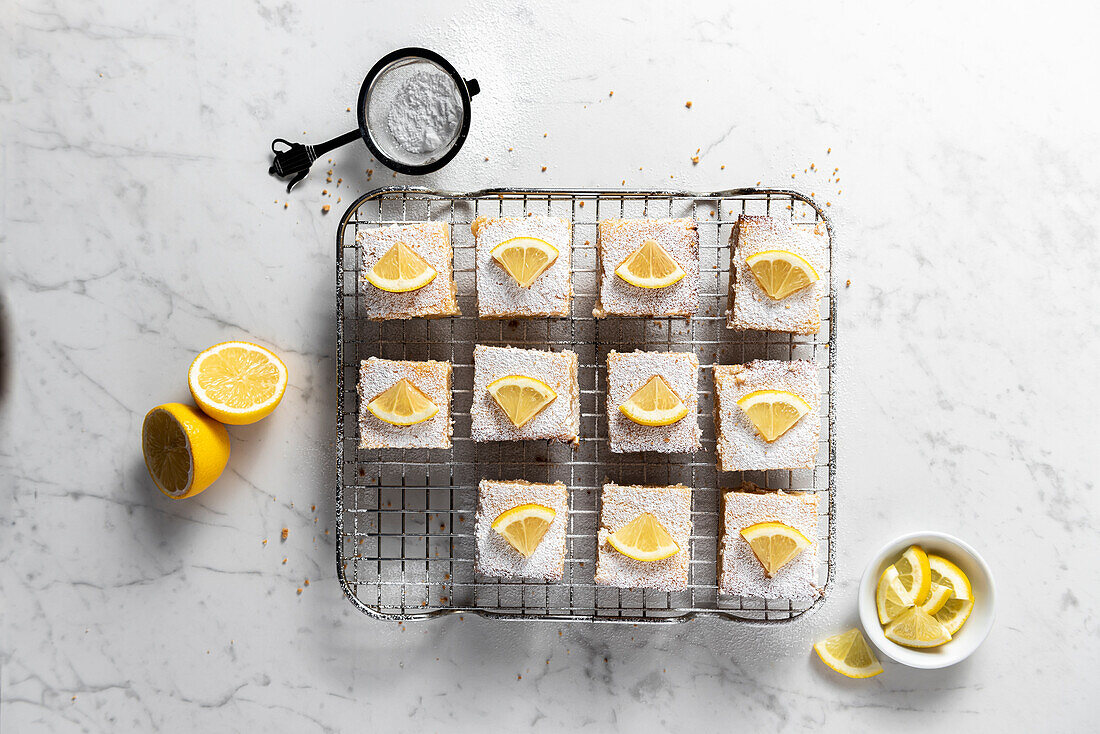 Tray of lemon bars with icing sugar and lemons