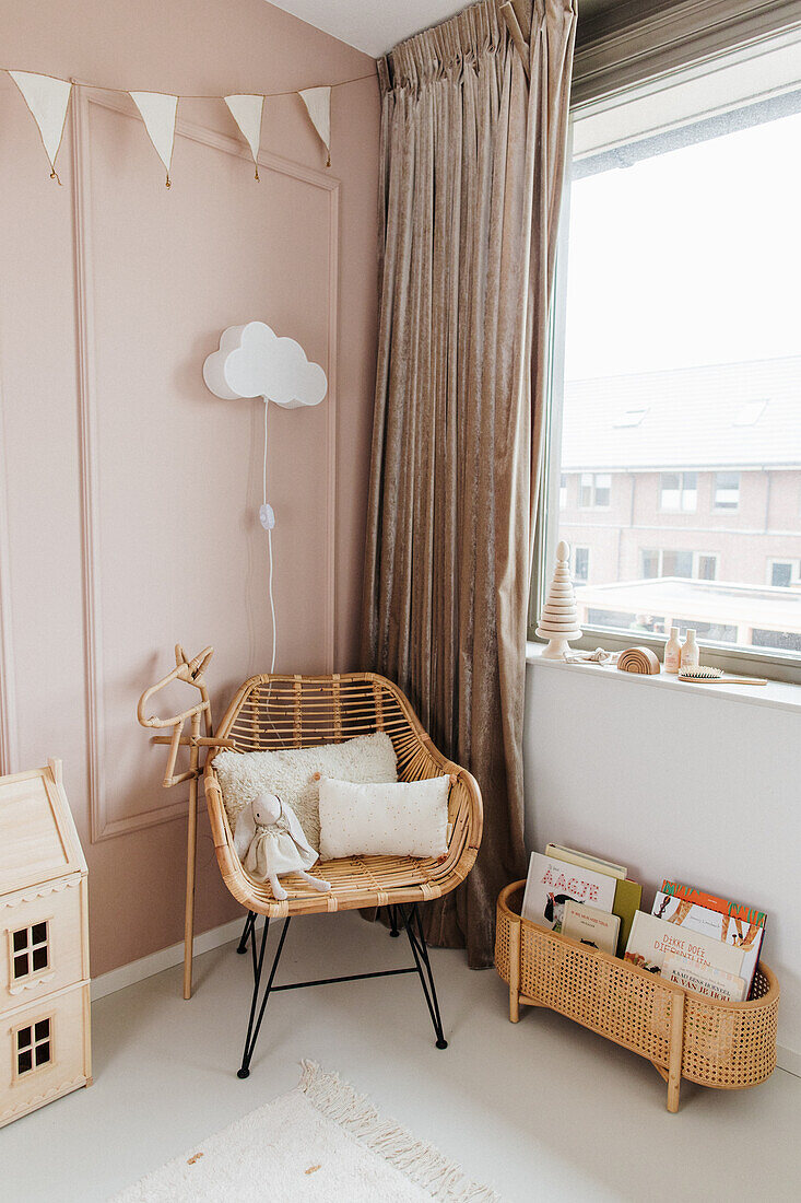 Rattan armchair next to window with floor-length curtain in nursery