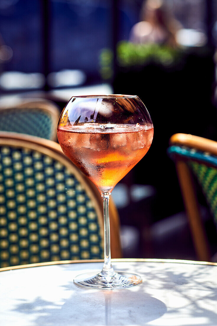 Aperol Sprizz with ice cubes on outdoor table