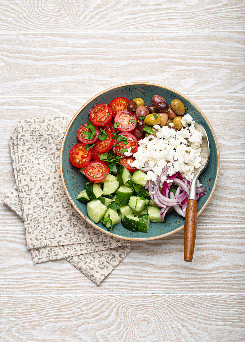 Griechischer Salat mit Tomaten, Feta, Gurken, Oliven und roten Zwiebeln