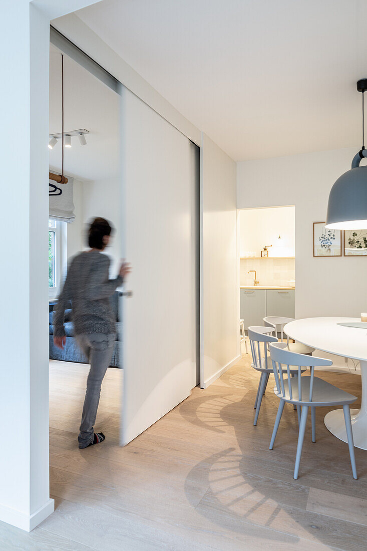 Woman pushing open movable wall between living room and dining room