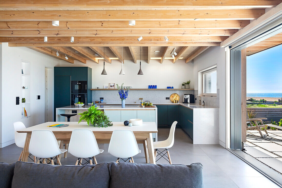 Shell chairs around dining table in open plan living room with kitchen