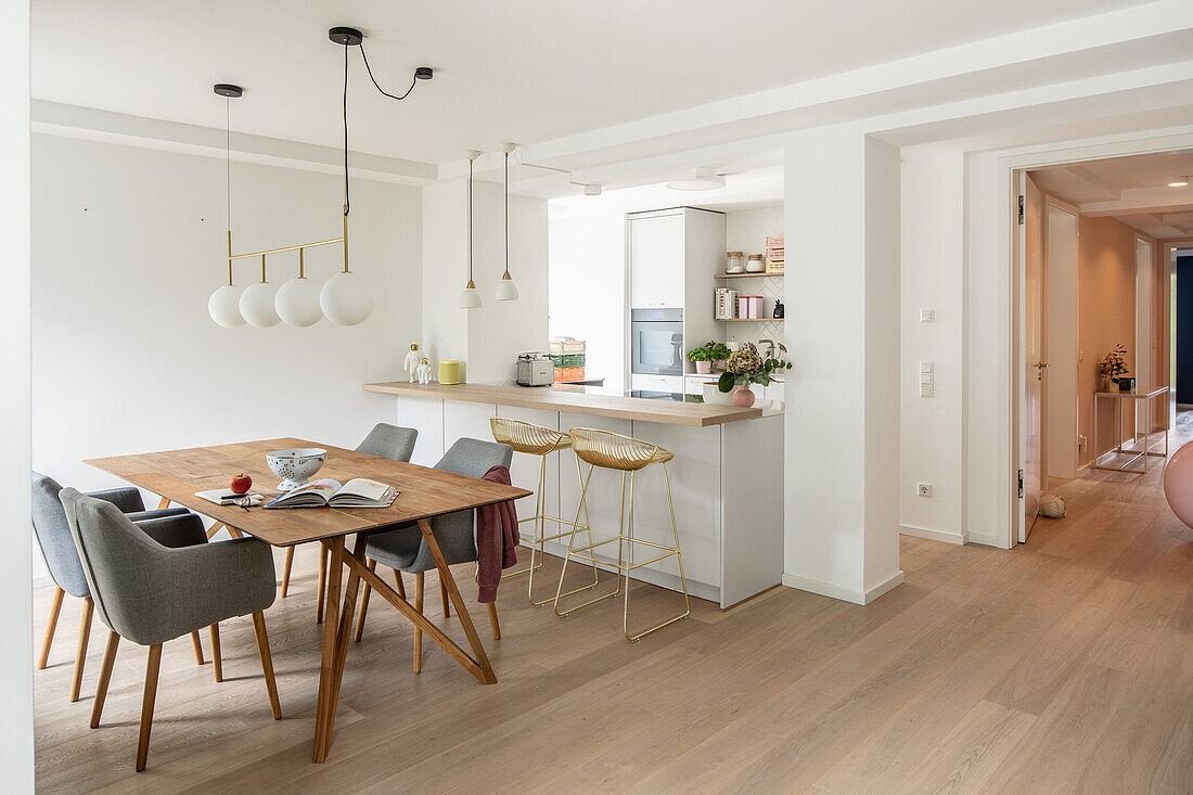 Dining area next to white kitchen with breakfast bar