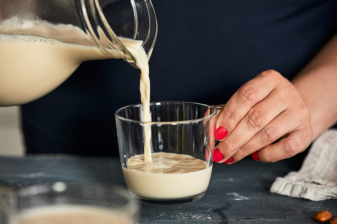 Selbstgemachte Mandelmilch in ein Glas gießen