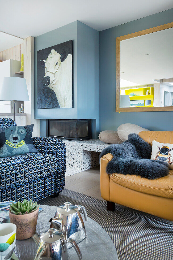 Blau-weiß bezogenes Sofa und hellbrauner Ledersessel im Wohnzimmer
