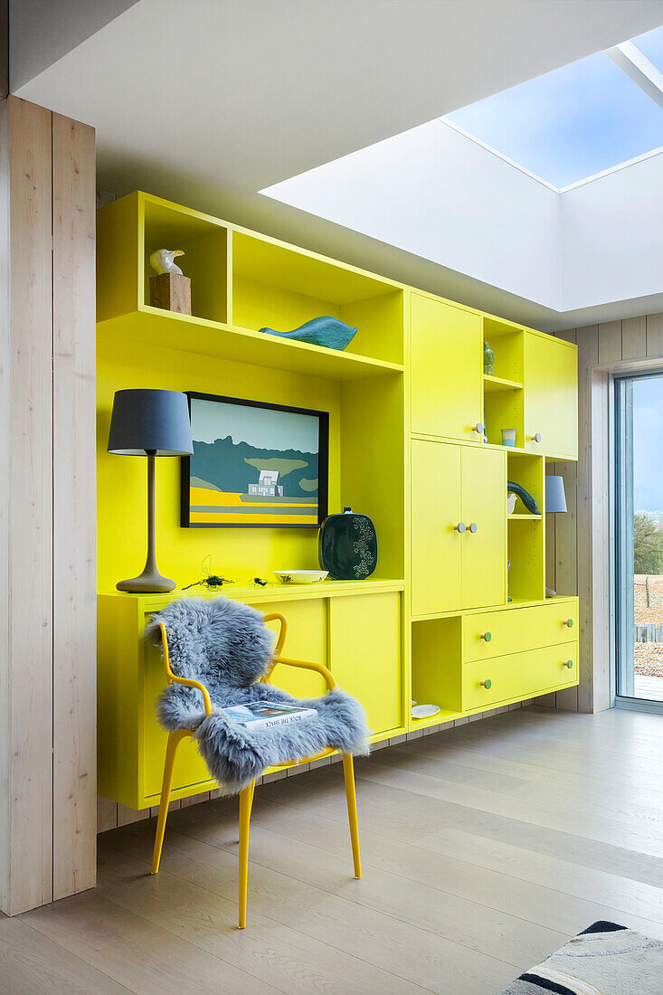 Lime-green fitted cabinets and chair with fur blanket in open-plan interior with skylight