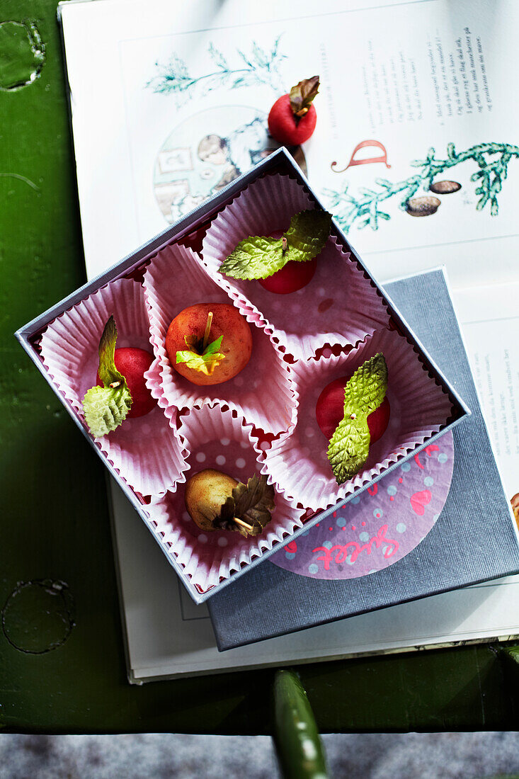 Box with miniature apples on an open book