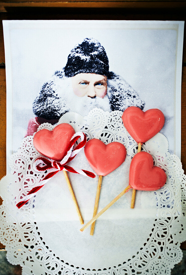 Heart-shaped lollipops on lace paper in front of Father Christmas illustration