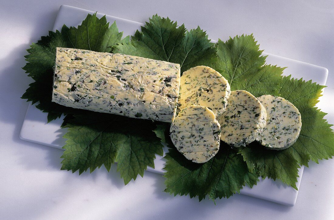 A roll of herb butter, cut into on vine leaves