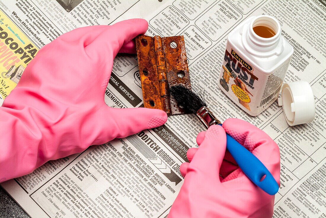 Rust remover being applied to rusty hinge