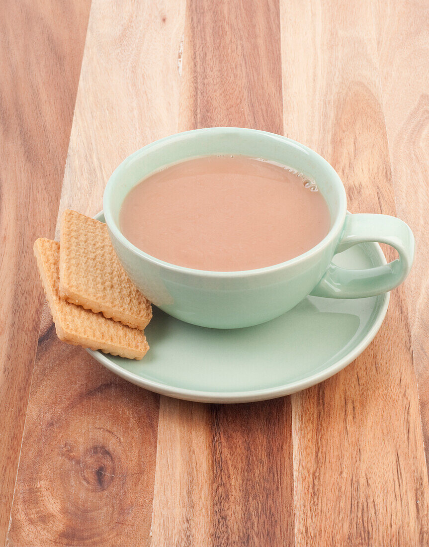 Cup of milky tea with two biscuits