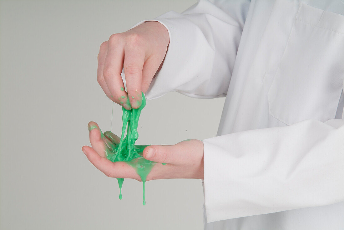 Man in lab coat holding green slime