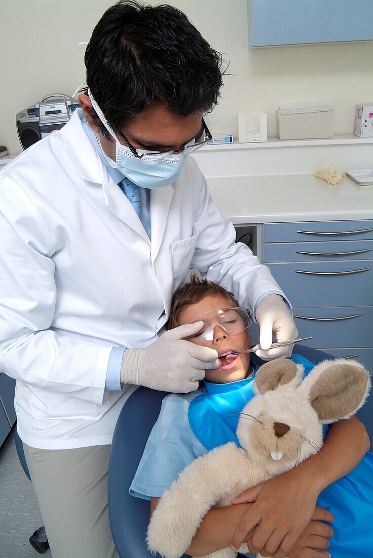 Dentist wearing mask holding mirror in boy's mouth