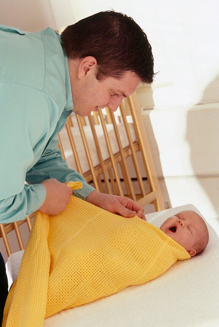 Father wrapping baby girl in blanket