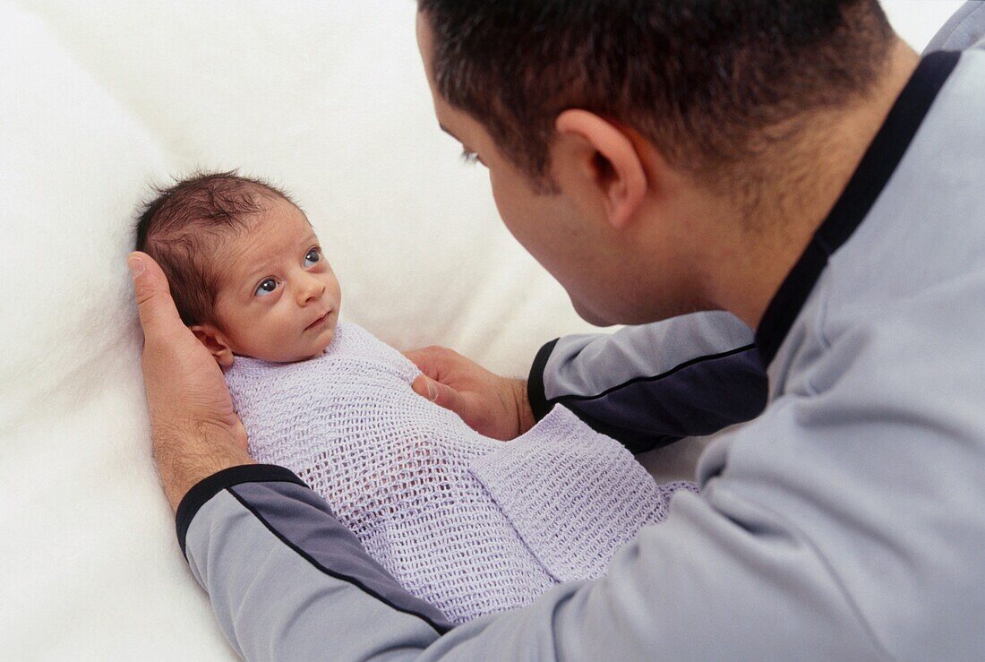 Man wrapping baby boy in blanket