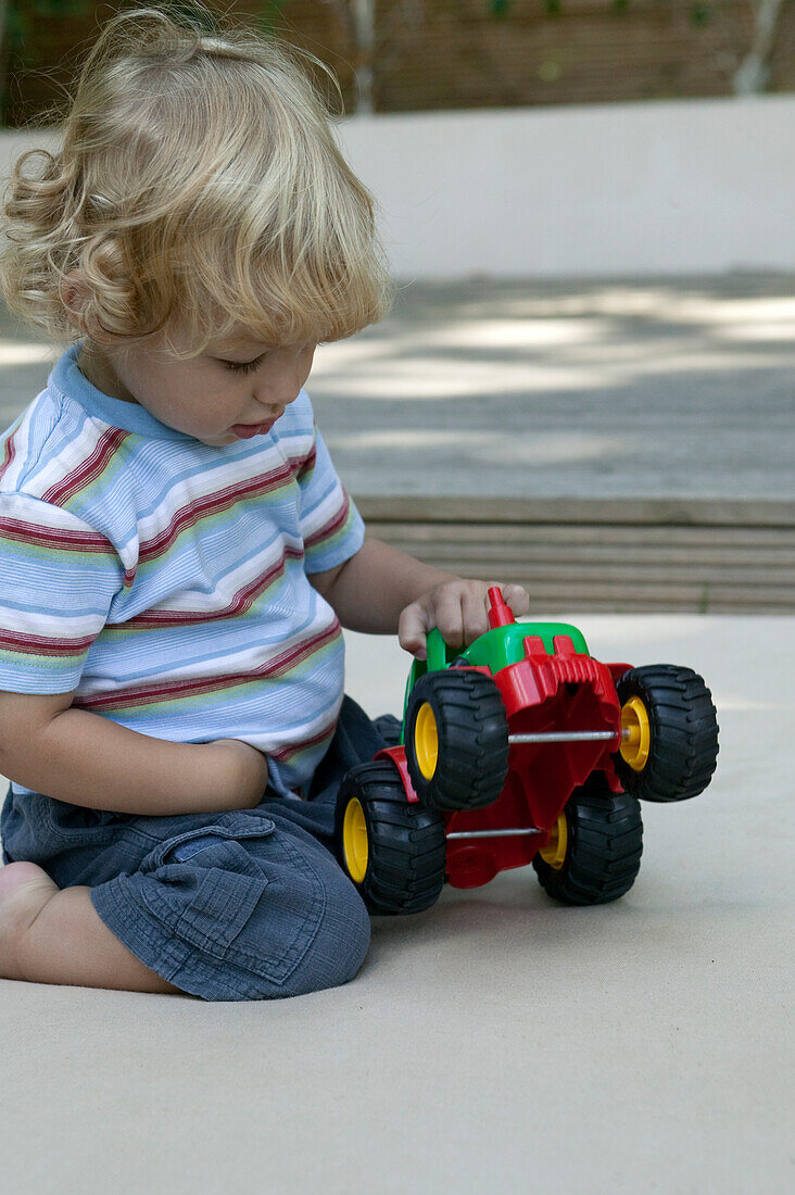 Toddler playing with plastic toy tractor