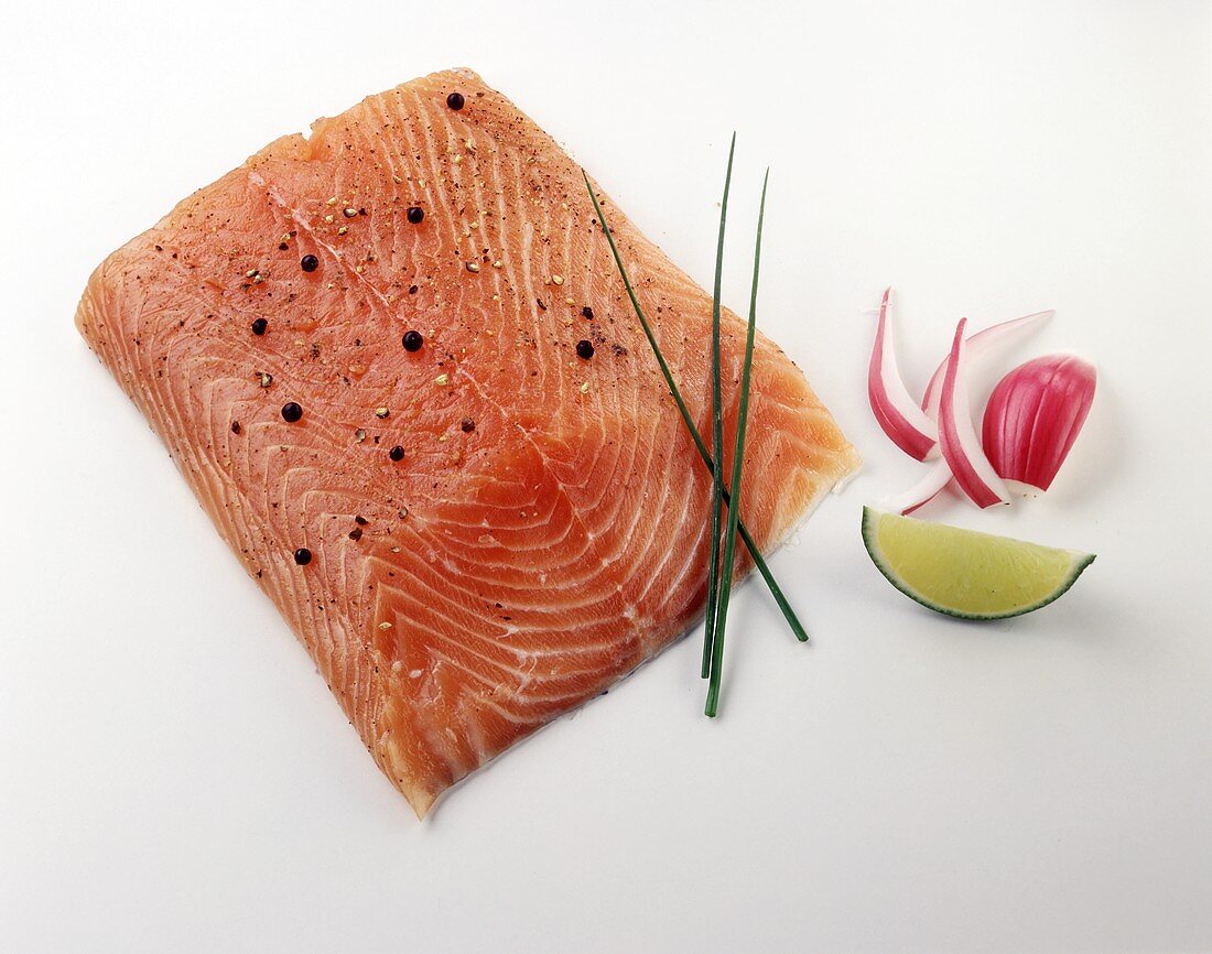 Piece of salmon with pepper, garnished with chives, onions