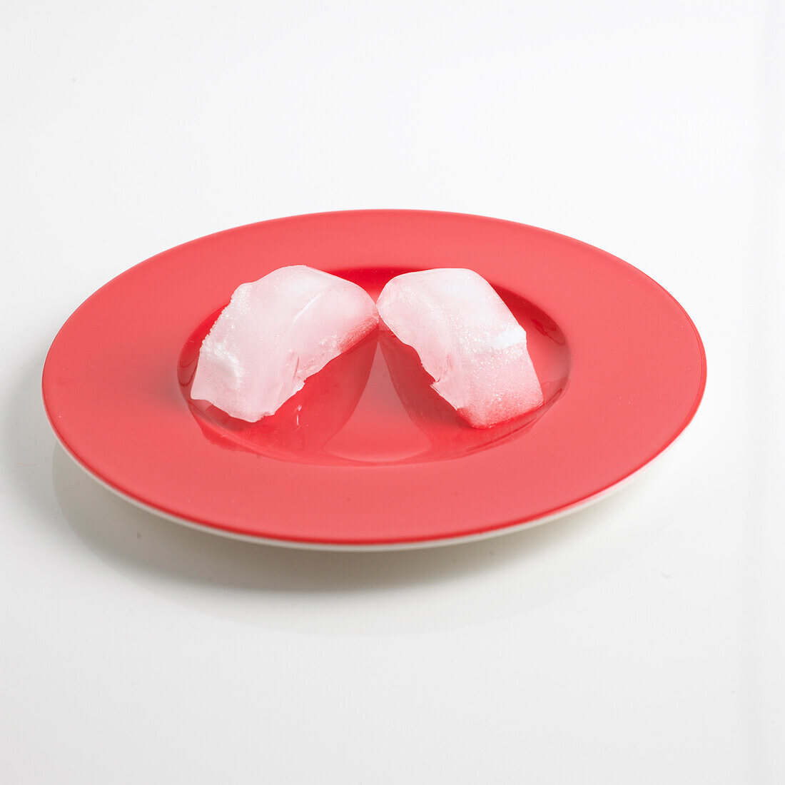 Red plate holding two ice cubes