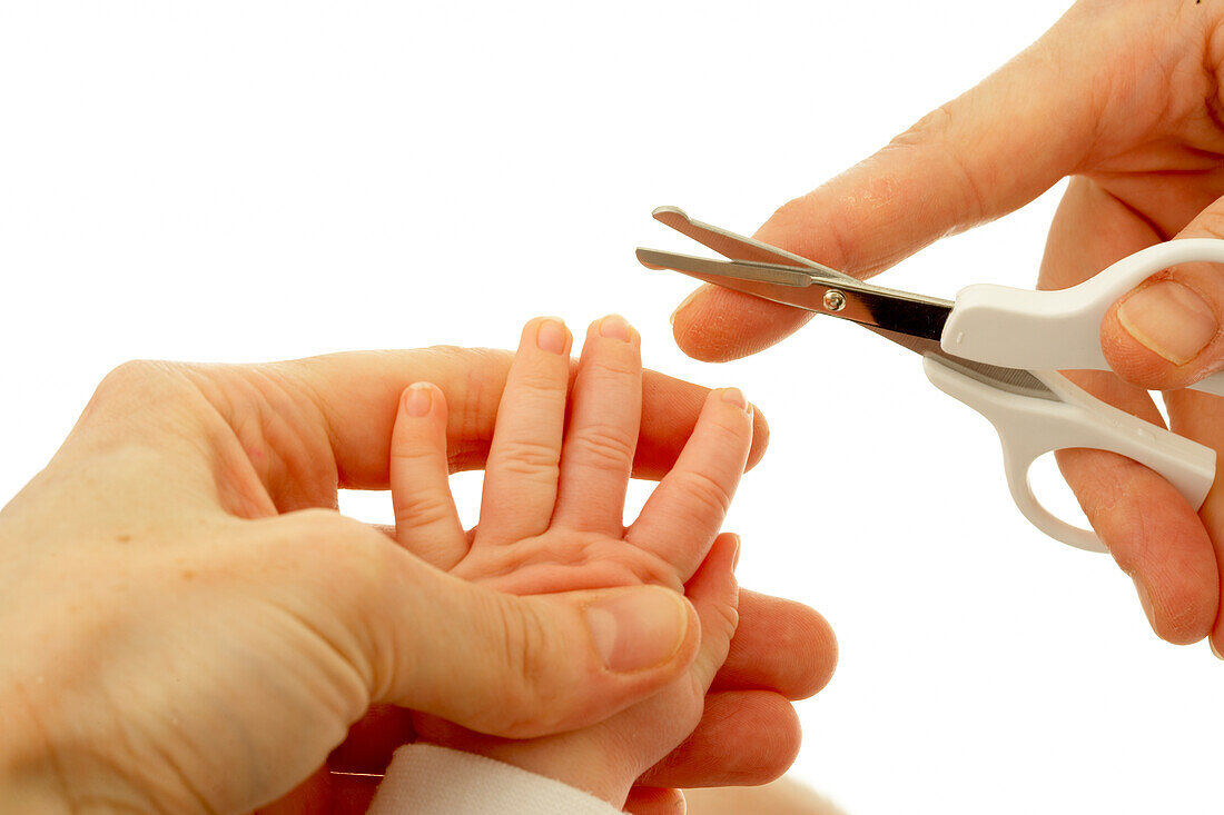 Woman's hands cutting baby's fingernails
