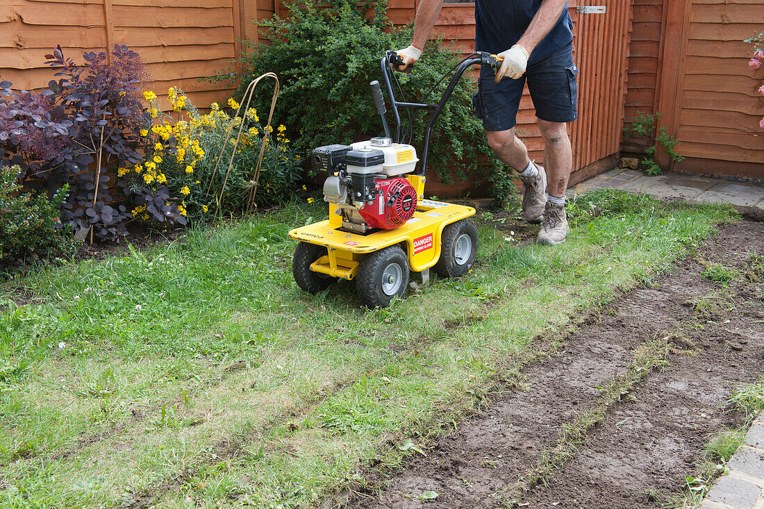 Man using turf cutting machine on lawn