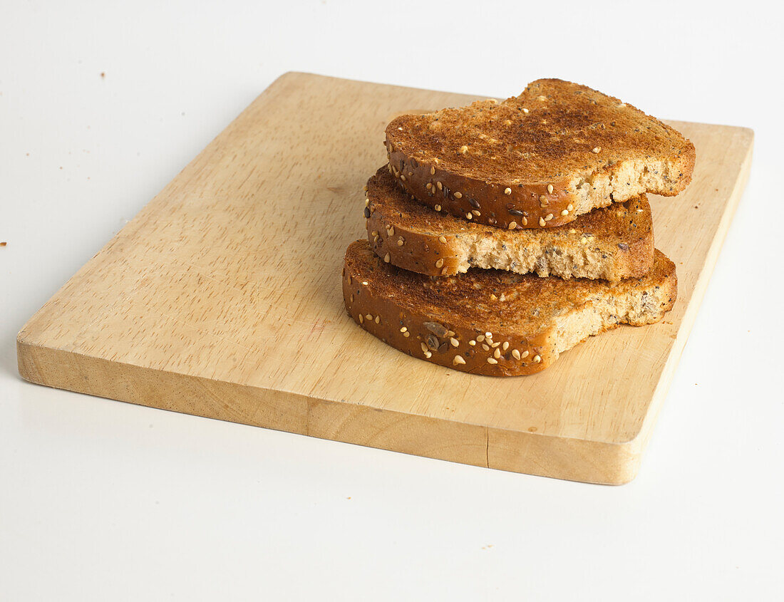Three slices of seeded toast on breadboard