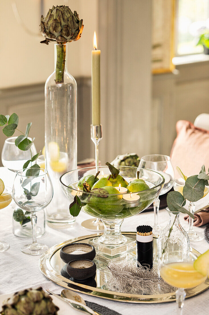 Pears and tea lights in bowl of water on festively set table