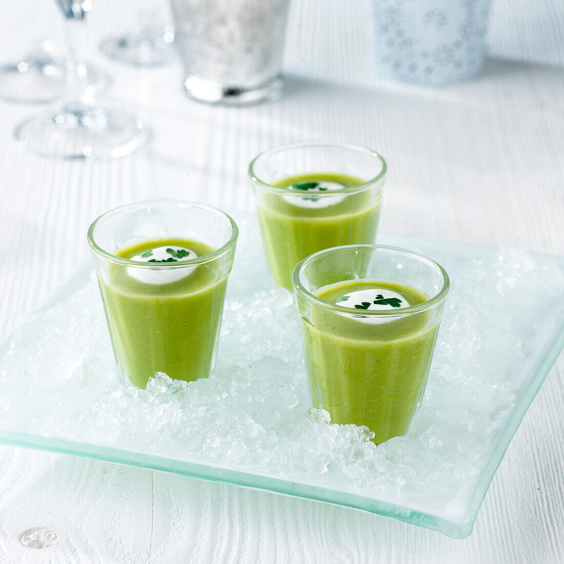 Glasses of chilled pea soup on tray of ice