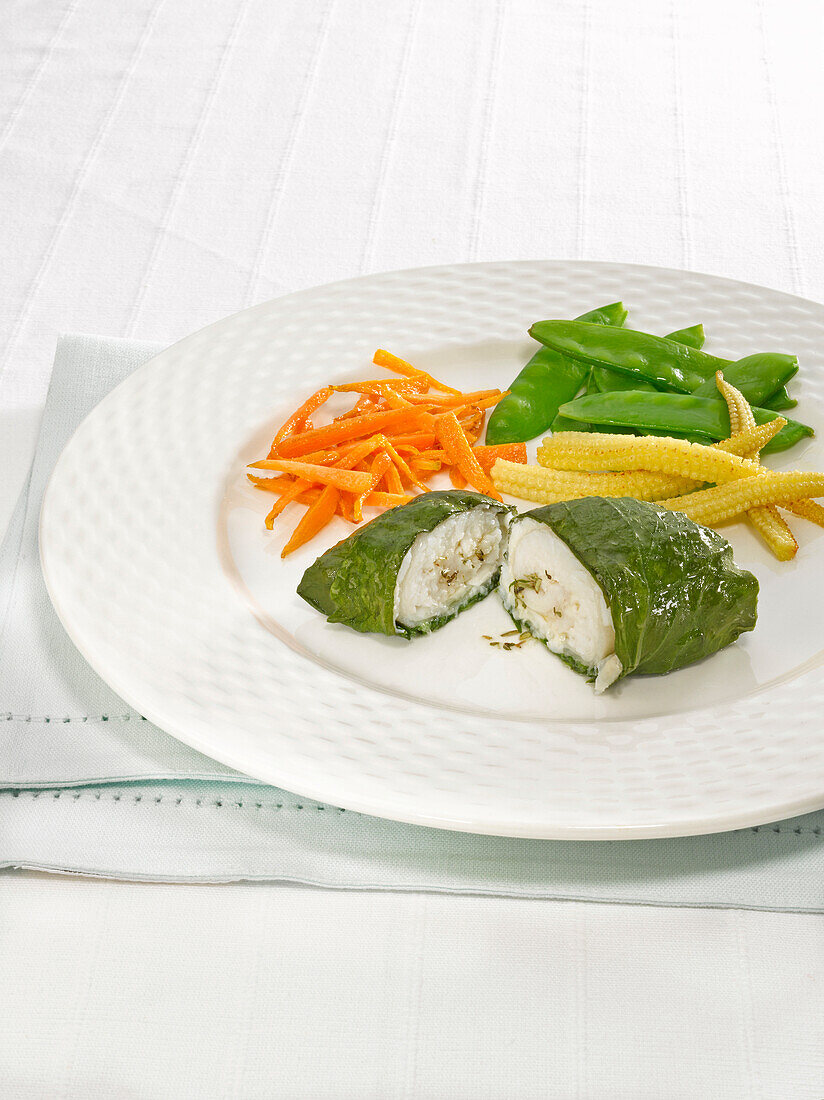 Sole wrapped in spinach with vegetable on plate