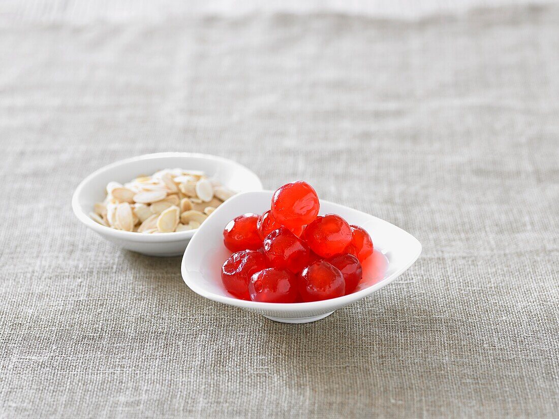 Glace cherries and almonds in small white bowls
