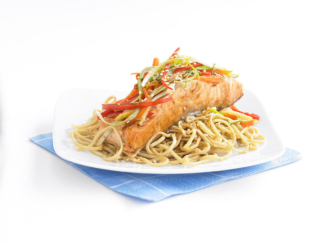 Salmon on bed of noodles with sliced vegetables on top