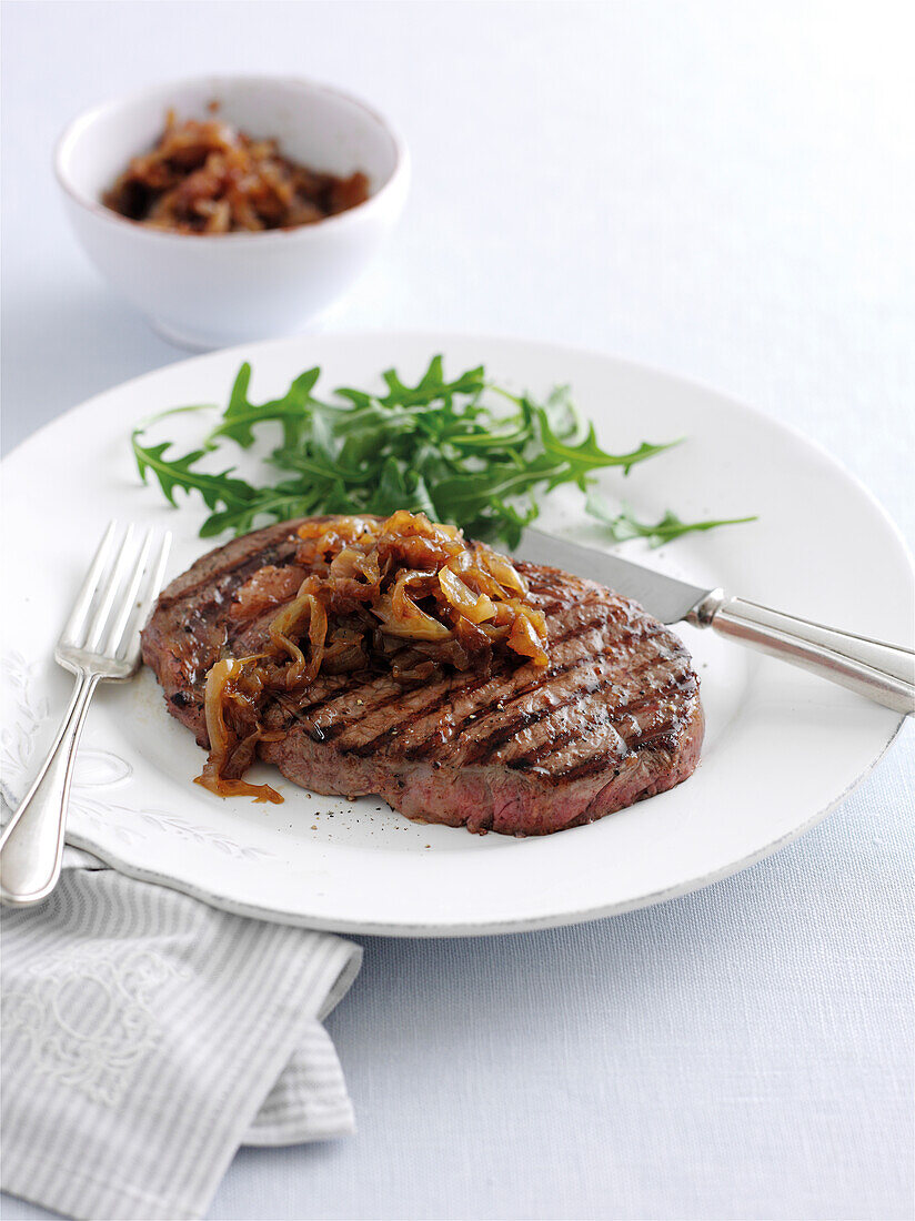 Grilled steak with onion marmalade and rocket garnish