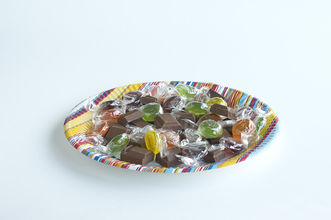 Boiled sweets and chocolate chunks on colourful paper plate