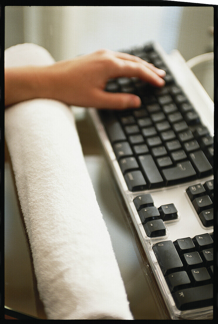 Typing on computer keyboard with wrist resting on towel
