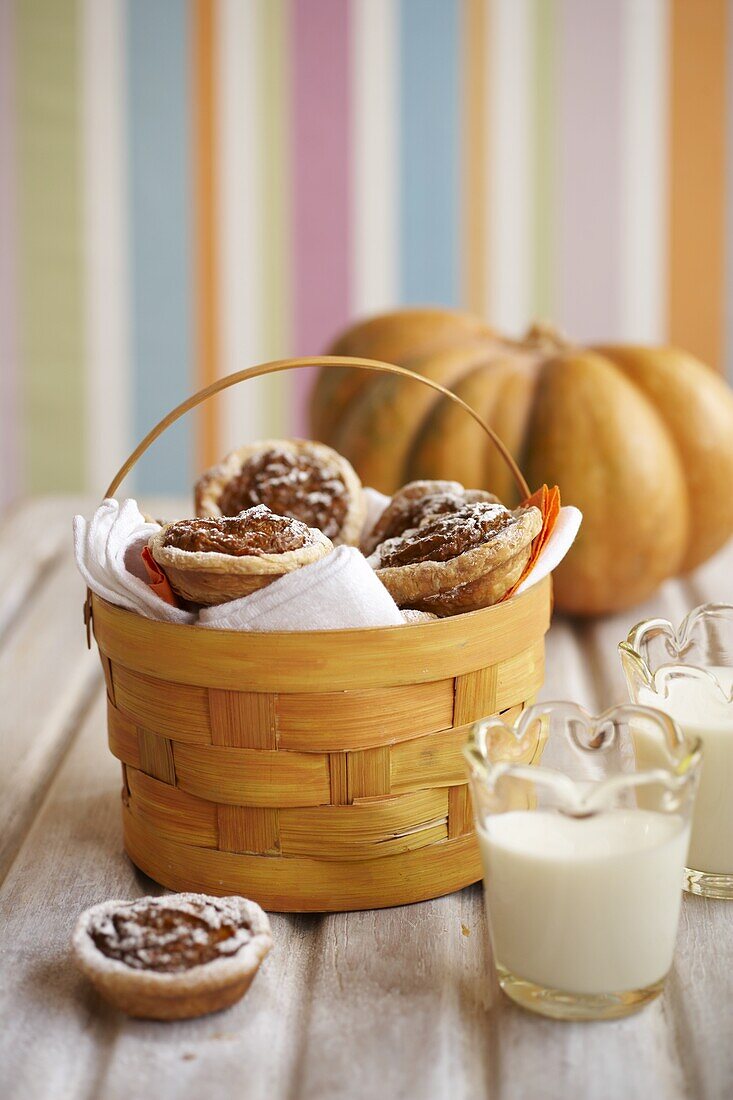 Mini pumpkin pies in basket, with glass of milk and pumpkin