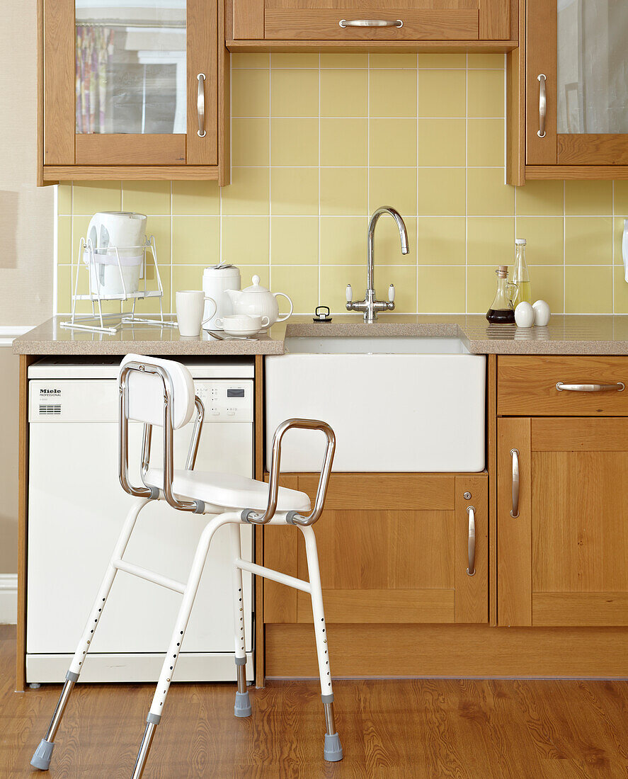 Using a chair or stool for washing at basin in kitchen