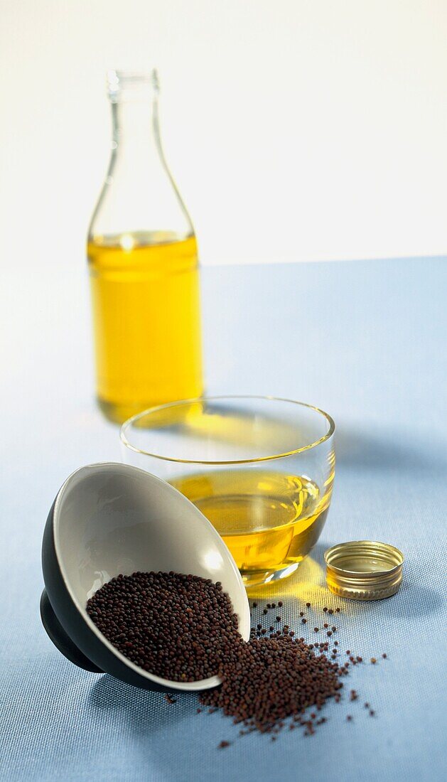 Brown mustard seeds and yellow mustard oil in glass